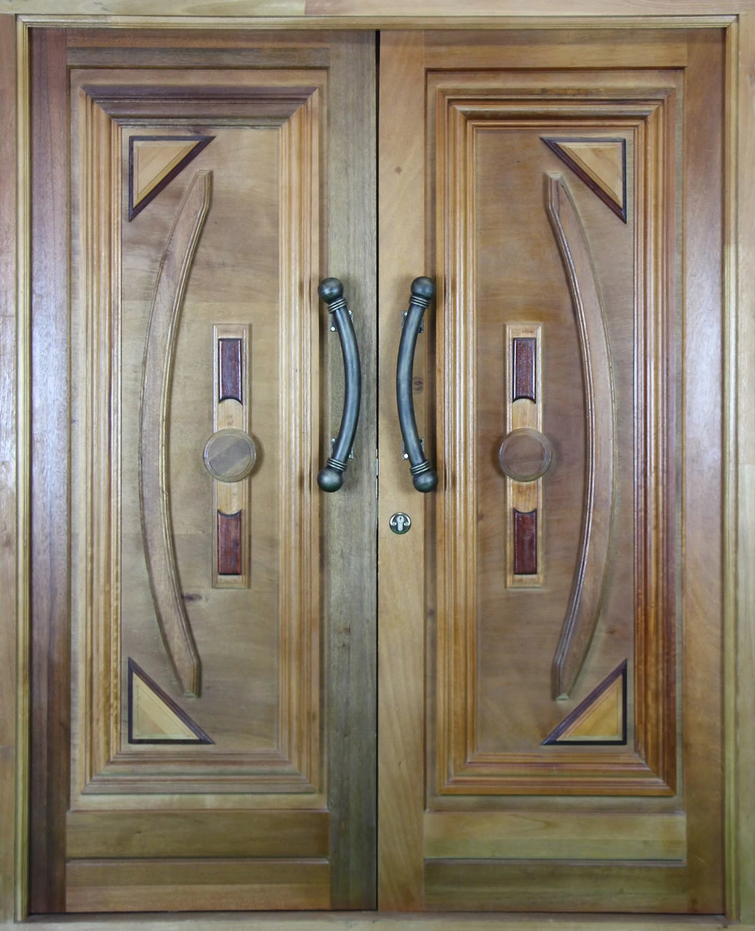 Statement entry doors with shield motif, natural wood tones, and black hardware