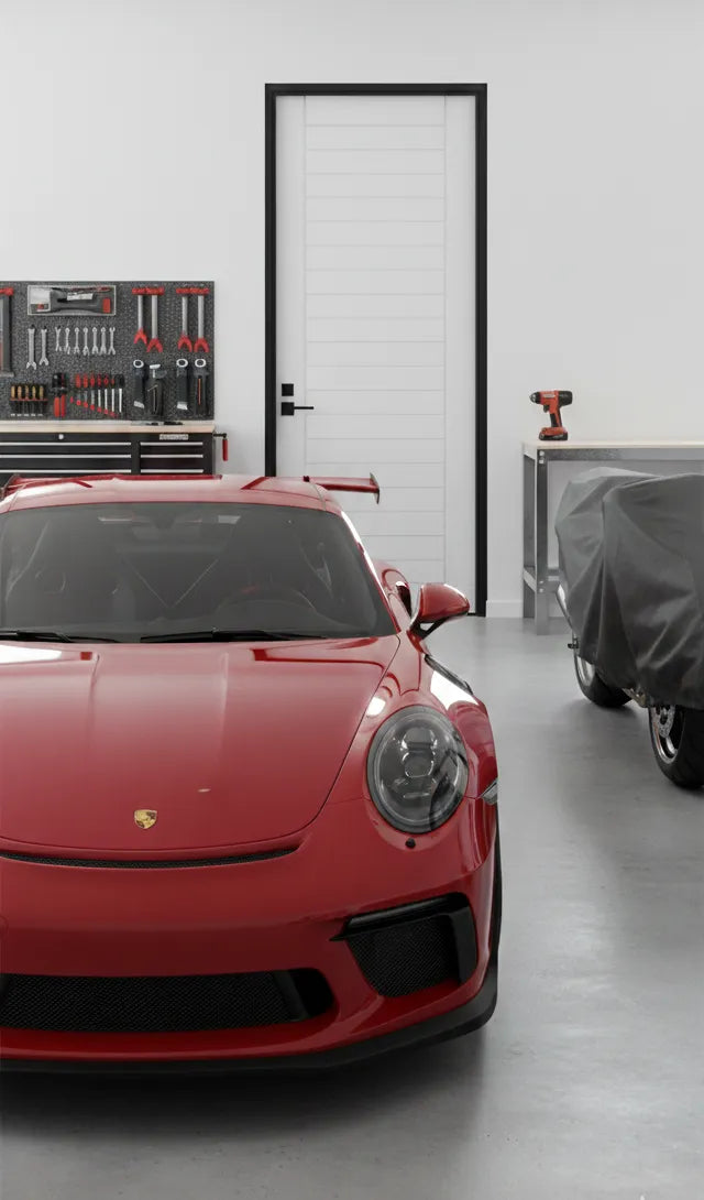 Elba Grooved door in the background of a Red Porsche car in a garage with tools and another car covered in the background.