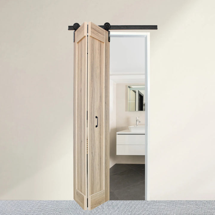 Sahara bi-fold barn door shown in open/folded position on black powder-coated aluminium sliding track to reveal a modern bathroom interior behind it.